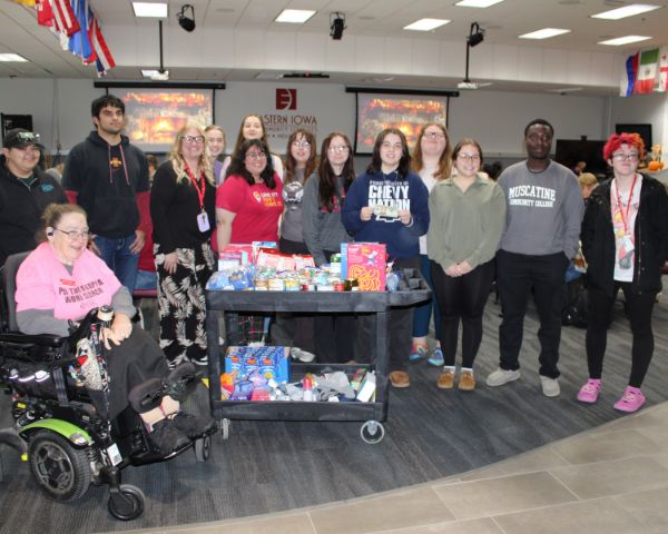 A group of students, staff and EICC Associate Professor Lori Sheppeard stand in a group behind a large cart of food they collected to give to local families.