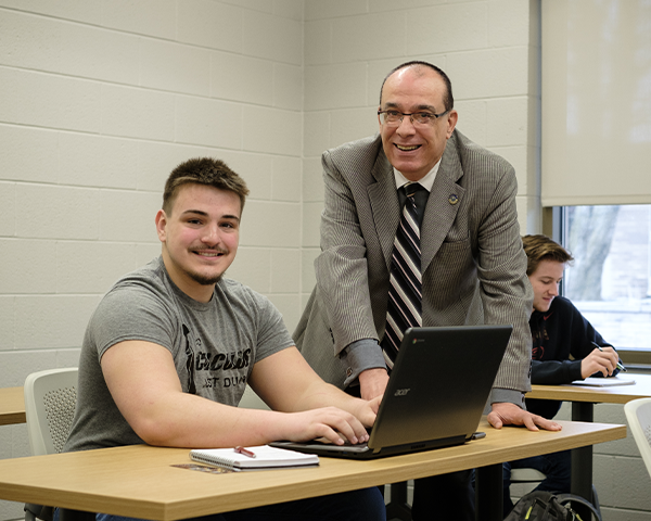 Smiling student sitting at desk with instructor